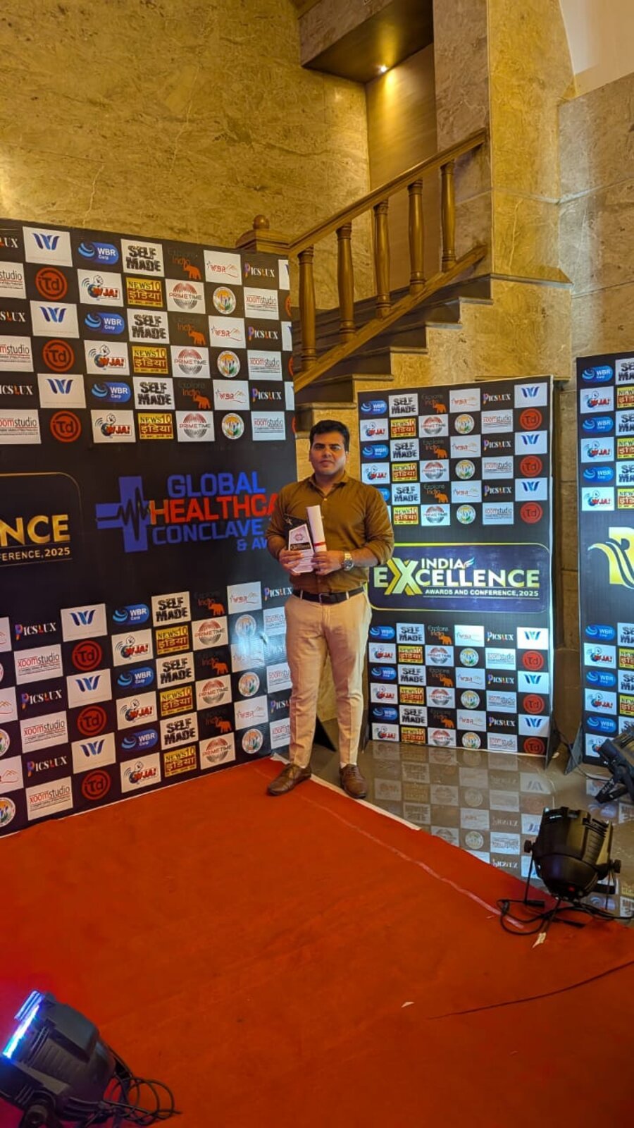 A Brains Iconic Charitable Trust representative holding the India Excellence Award trophy.