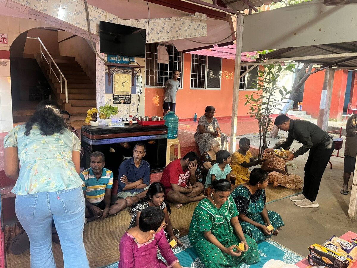 A Brains Iconic Charitable Trust volunteer distributing essentials to an elderly resident at a care home.