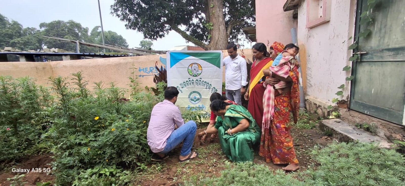A Brains Iconic Charitable Trust volunteer planting a sapling alongside community members in Keonjhar district.